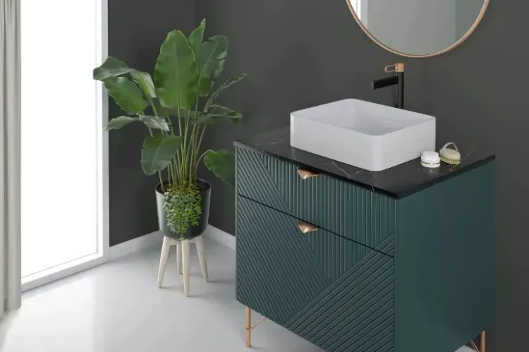 Łazienka z czarną baterią FDESIGN, zieloną szafką, rośliną i okrągłym lustrem