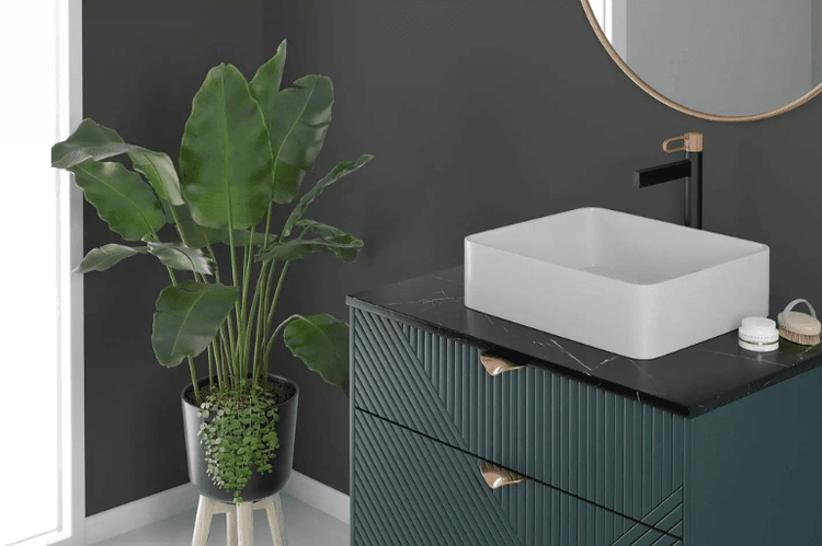 Łazienka z zieloną szafką, czarną baterią FDESIGN ze złotym detalem i nablatową umywalką